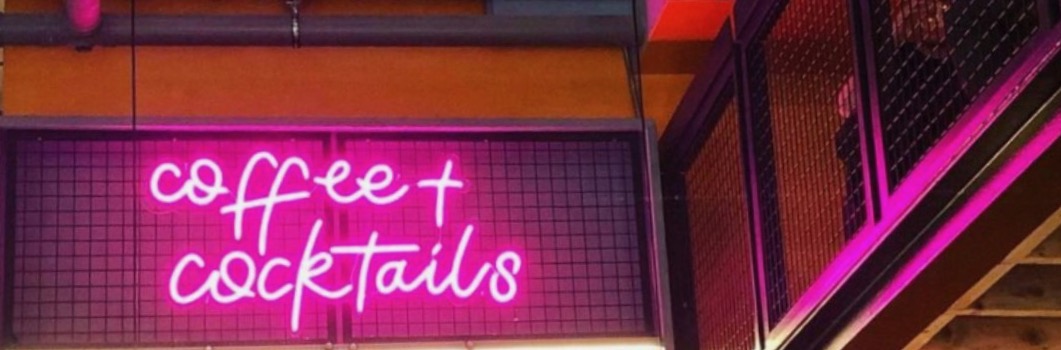 Pink neon sign saying Coffee and Cocktails at Society in Manchester city centre