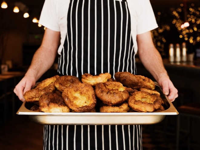 A chef holding a tray of Yorkshire puddings at Frederiks in Liverpool.