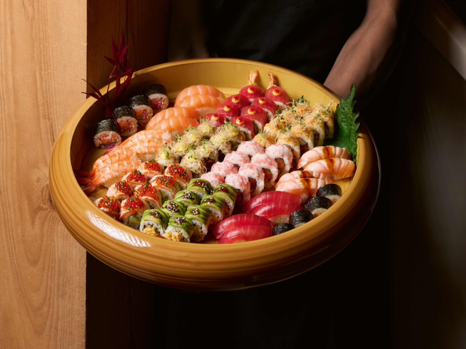 A wooden tray filled with brightly coloured sushi at Sticks n Sushi in Manchester.