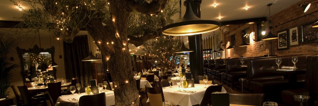 Olive trees and fairy lights create a magical interior at Gusto Heswall, a recommended Italian restaurant on The Wirral.