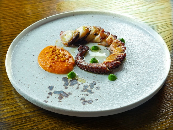 A dish of grilled octopus whole tentacle with romesco sauce, parsley purée and smoked almond crumble at Barnacle in Liverpool.