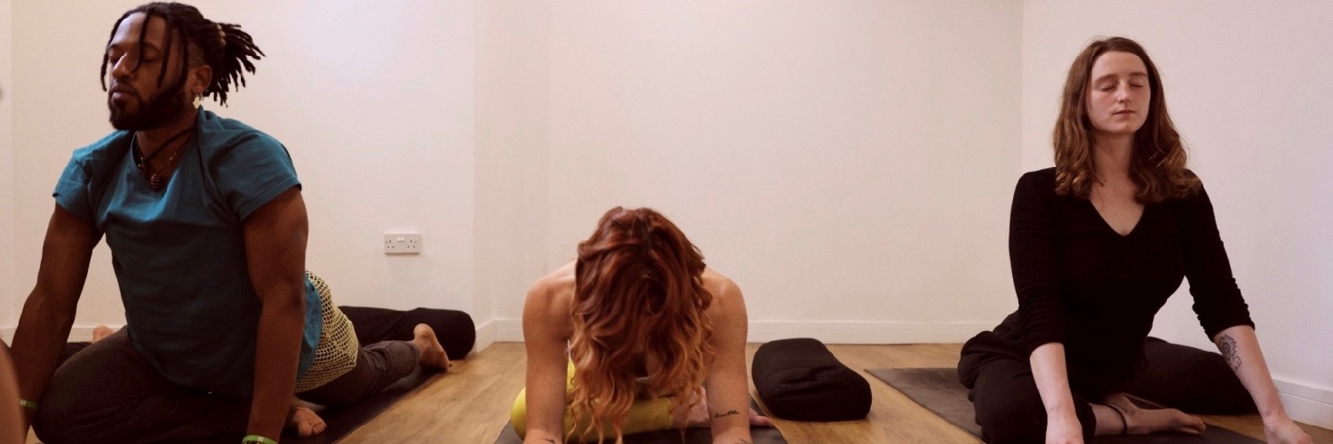 Three people practising yoga at Yoga Soul - a yoga studio in the Northern Quarter, Manchester