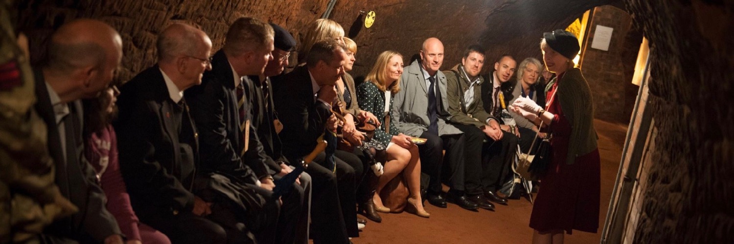 A tour group sitting on a bench in the tunnels at Stockport Air Raid Shelter