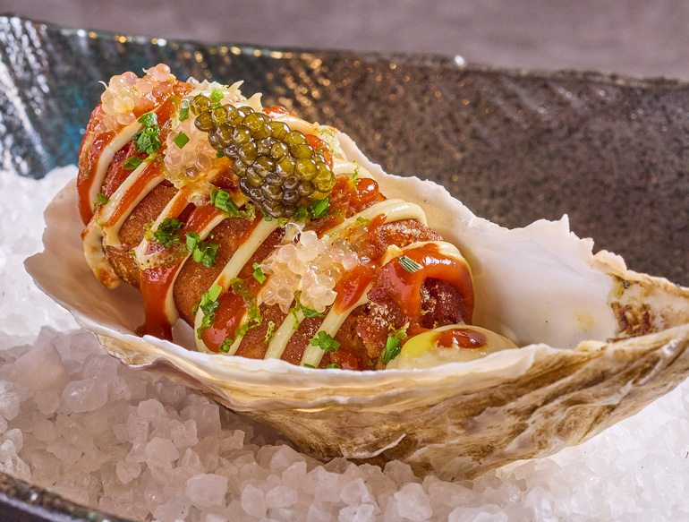 Jersey royal potato, topped with yuzu sour cream, miso, seaweed butter, and caviar, served in an oyster shell at Kaji