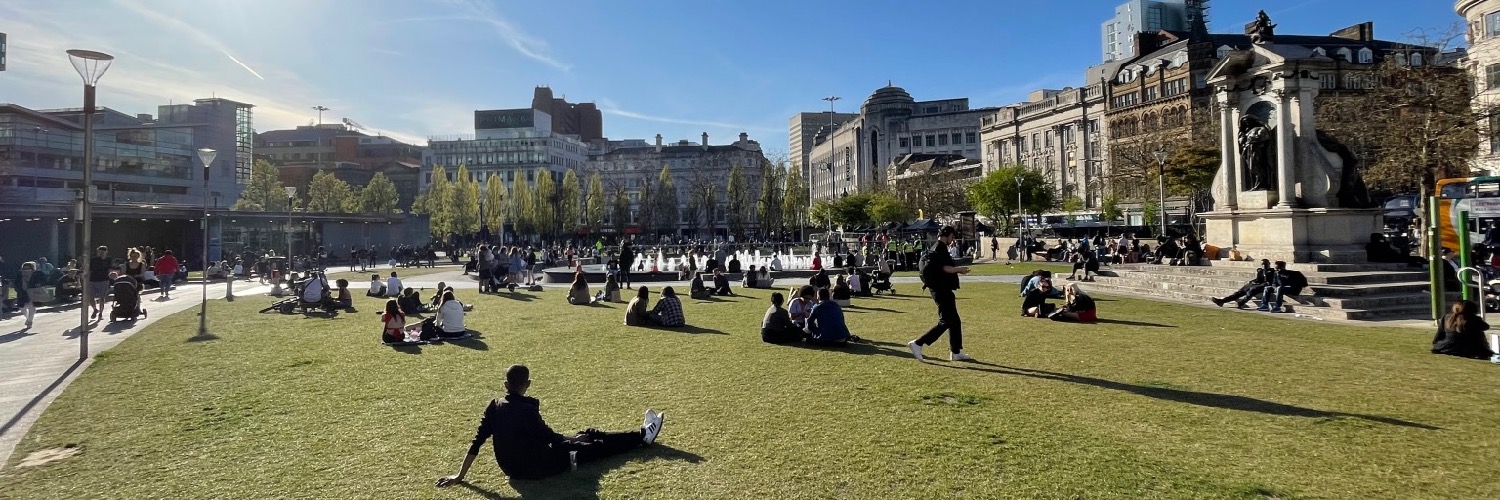 People relaxing on the lawns in Piccadilly Gardens, Manchester.