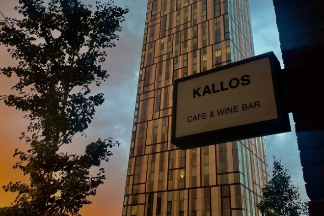 Kallos cafe & Wine Bar at sunset with a high-rise building in the background