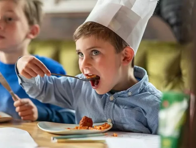 Child in Chef's hat eating meatballs at Banyan