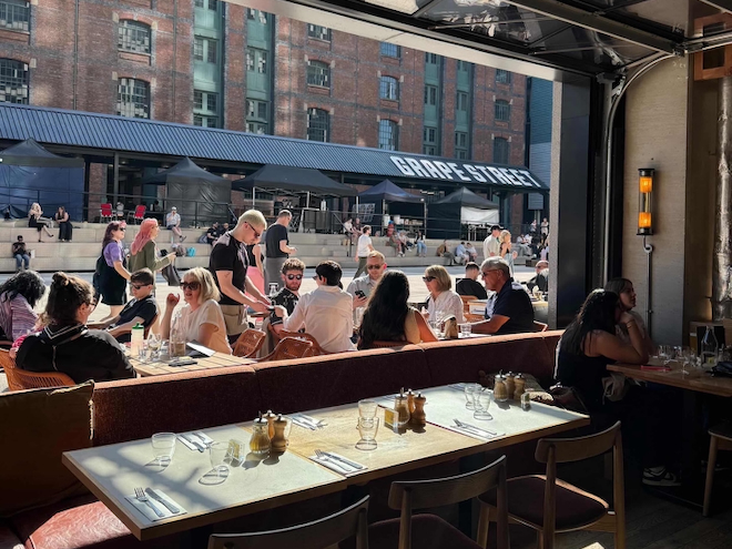 People sitting in the sun on the terrace at Caravan in Manchester.