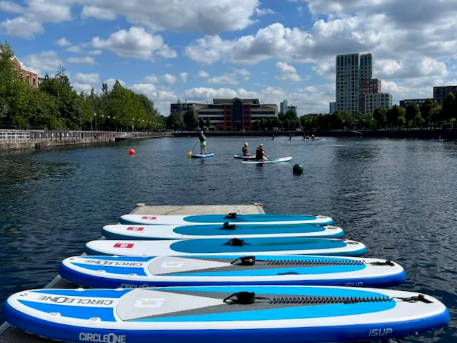A line of paddleboards on a jetty at Salford Watersports Centre.