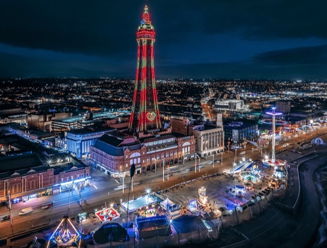 Blackpool Tower at night in winter with the Christmas By The Sea ice rink and market stalls in the foreground.