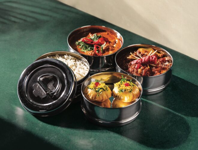 Four metal bowls filled with Indian tiffin food from Mowgli.