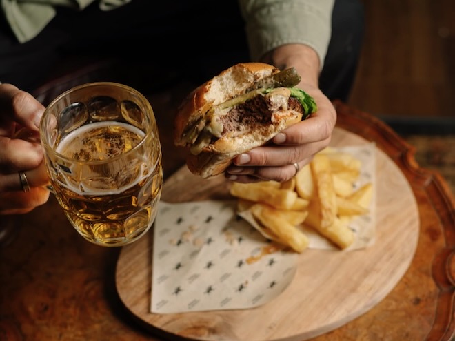 Man with a burger and a pint of lager at Horse & Jockey.