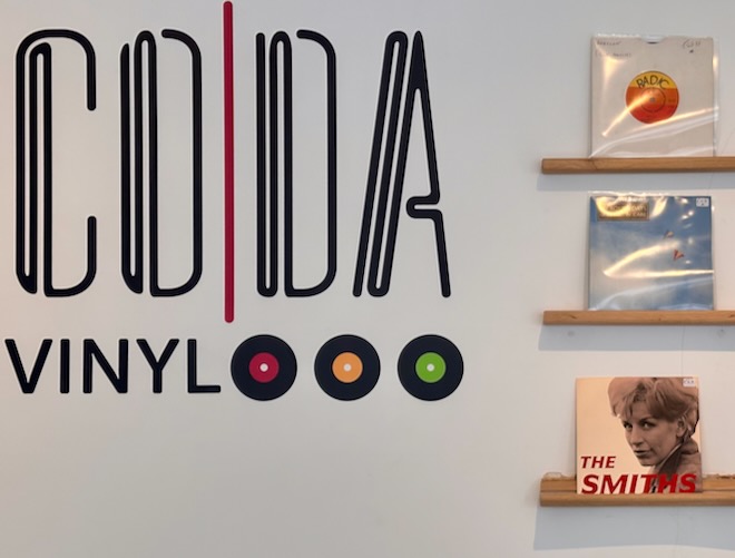 The Coda Vinyl logo painted on the wall of the shop next to some 7-inch singles.