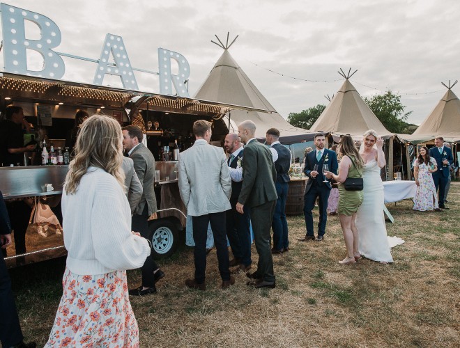 Wedding guests chatting outside by the Airstream trailer bar