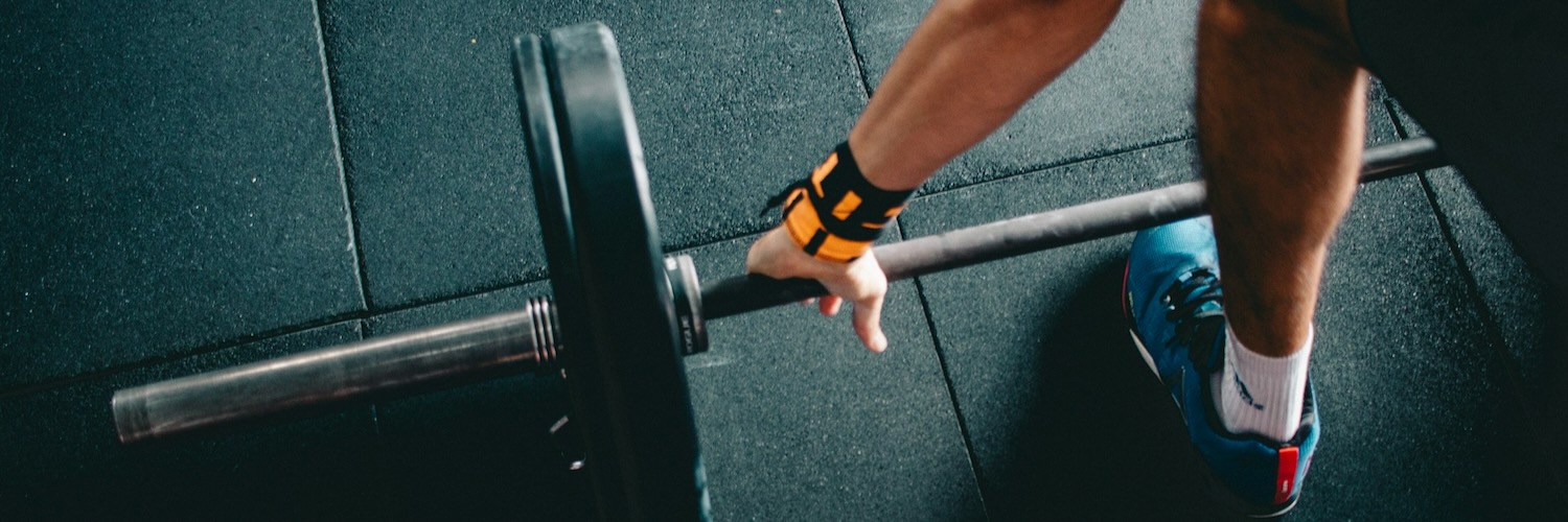 A man preparing the lift a barbell off the gym floor.