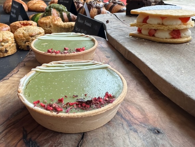 Pistachio tartlet displayed in the window with more cakes at Libby's Bread & Wine.