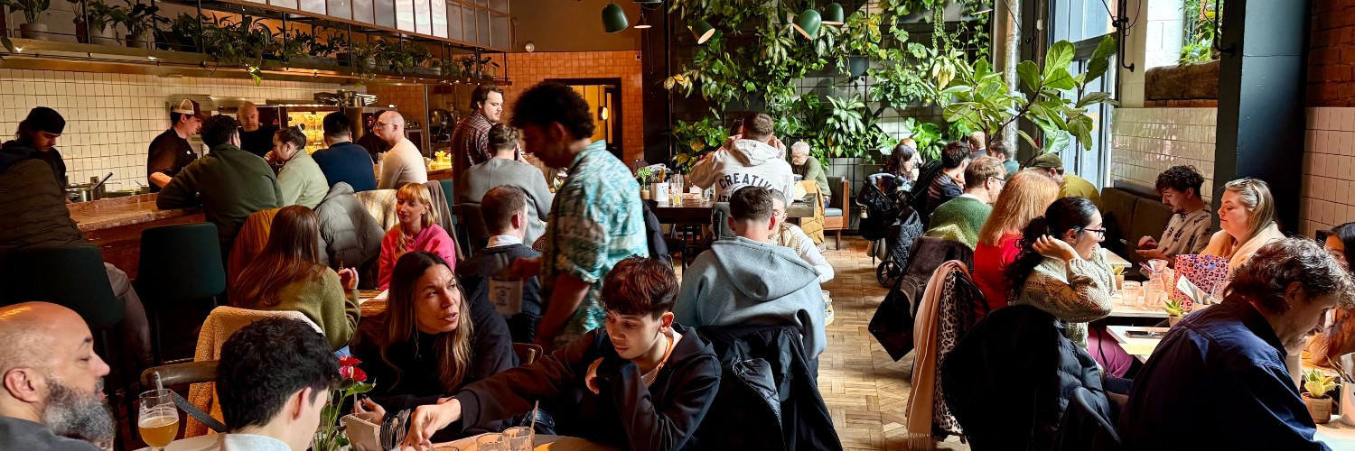 Interior of Butter bird with buzzy atmosphere, full tables and wall of greenery