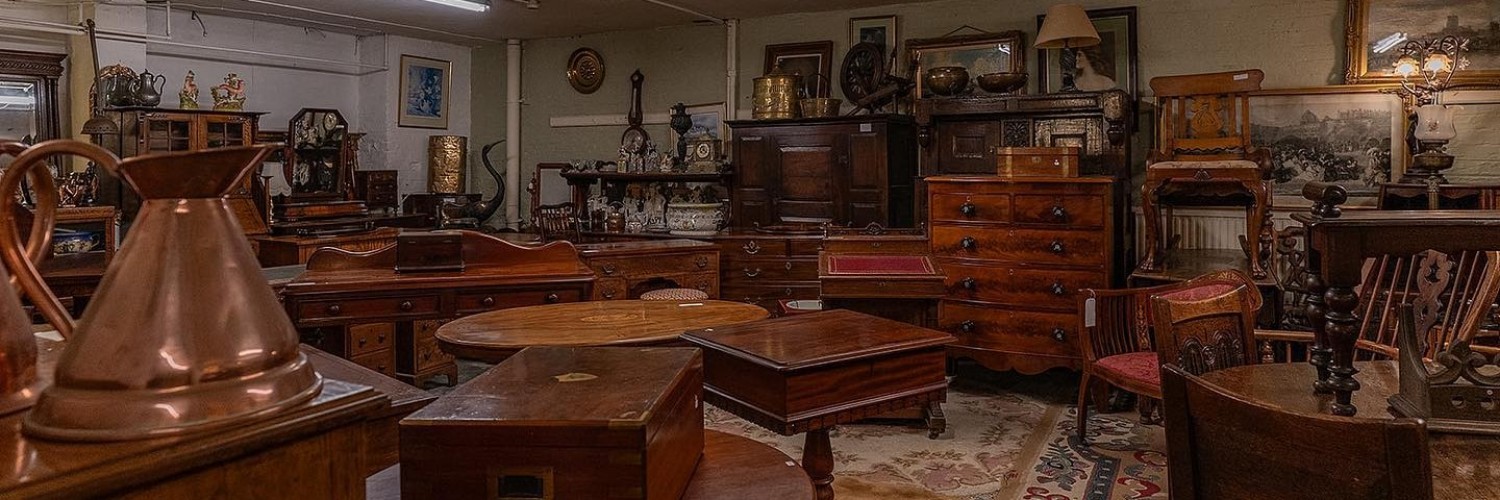 A selection of wooden furniture including tables and chests of drawers at Levenshulme Antiques Market