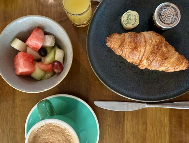 Dishes holding fresh melon, a croissant and coffee at Kimpton Clocktower Hotel