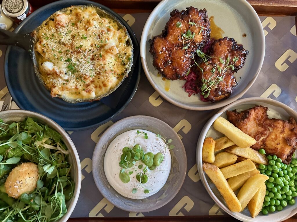 A tray of food from The Refuge including lobster mac n cheese, fried chicken and salad.