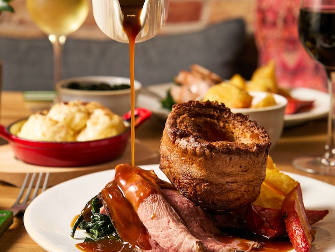 Gravy being poured onto a roast beef and Yorkshire pudding at Pip in Manchester.