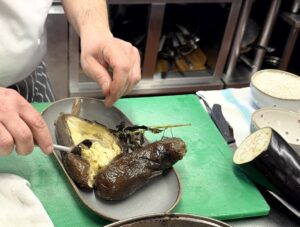 Chef Giuseppe Lombardo scooping out the flesh of a roasted aubergine