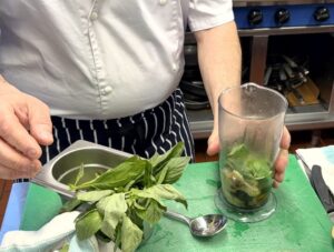 Adding basil, roasted garlic and roasted aubergine to a food processor