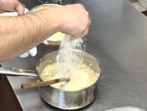 Adding handfuls of parmesan to the risotto