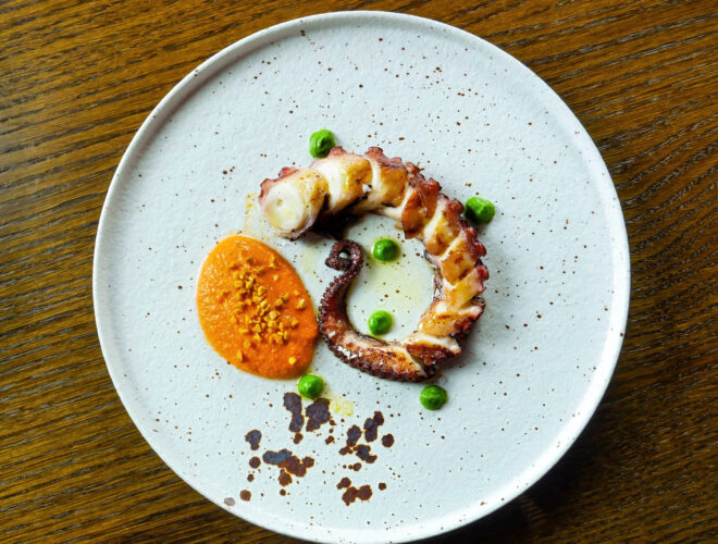 A dish of grilled octopus whole tentacle with romesco sauce, parsley purée and smoked almond crumble at Barnacle in Liverpool.
