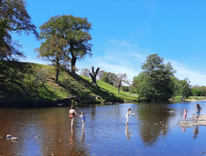 The river at Chatsworth with people playing in the water.