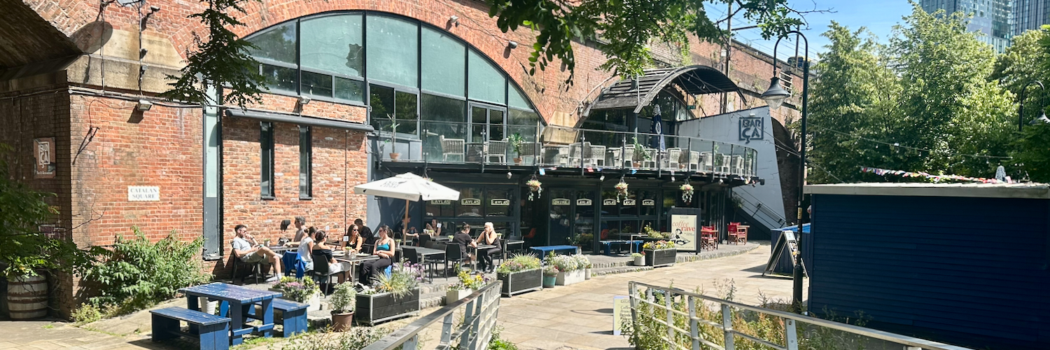 The exterior of Layla's Cafe in Castlefield, Manchester with people sitting outside in the sunshine.