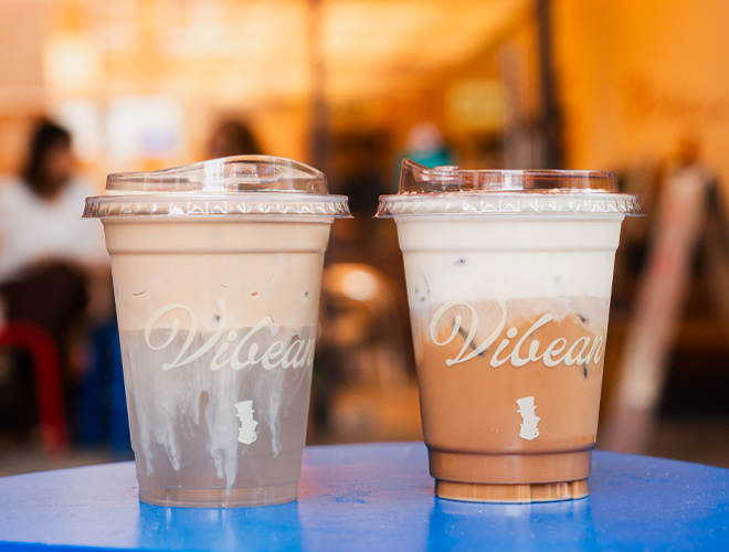 Two cups of iced coffee to takeaway ona blue table at Vibean, Manchester.