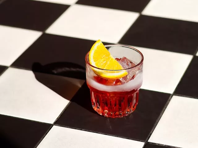 A short cocktail with a slice of lemon on ice on black and white chessboard tiles at The Morris in Manchester.