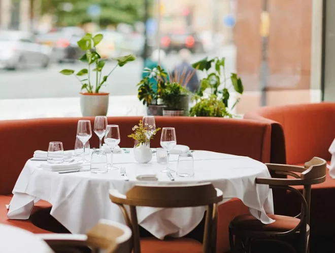 Curved orange booth seating at Don Giovanni with white linen tablecloth and glassware