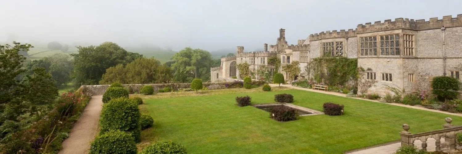 The exterior of Haddon Hall on a misty day, looking out over the gardens