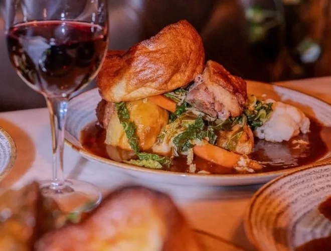A glass of red wine and a Sunday roast topped with a Yorkshire pudding at Ma Boyles